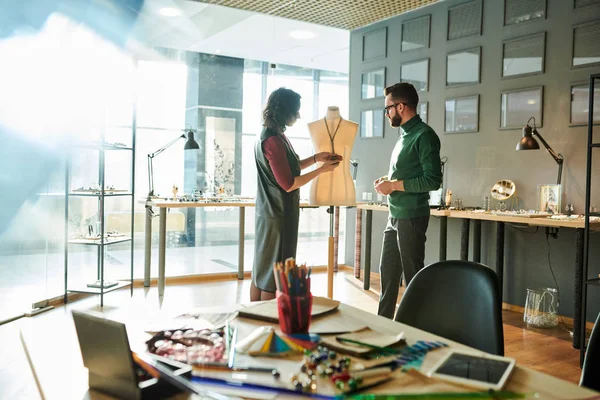 Portrait of two creative designers discussing luxury jewelry standing in sunlit office, copy space