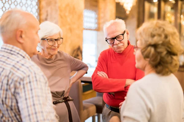 Sisältöryhmä Tyylikkäissä Asuissa Olevat Seniorit Seisovat Ympyrässä Kuuntelevat Tarkkaavaisesti Ravintolan — kuvapankkivalokuva