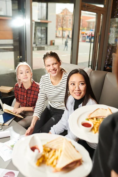 一群女学生在咖啡馆点菜 她们坐着看着服务员为他们送食物 — 图库照片