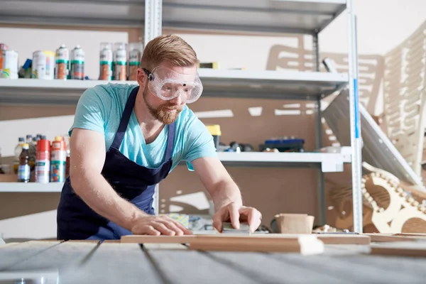 Young Bearded Carpenter Wearing Apron Glasses Sanding Wooden Parts Table — Stock Photo, Image