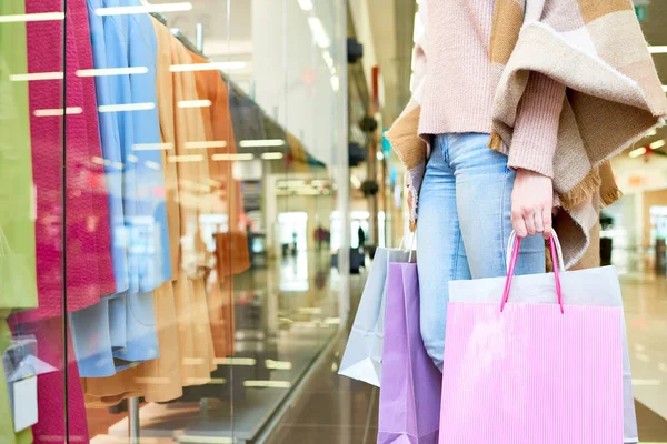 妇女拿着购物袋 站在商店窗口附近 穿着五颜六色的外套的特写 — 图库照片
