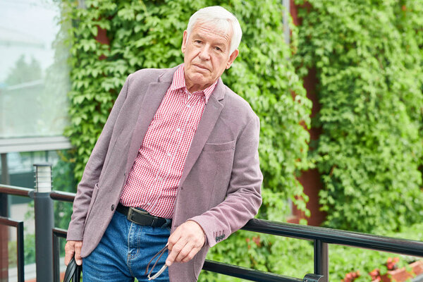 Waist up portrait of modern senior man dressed in business casual posing standing on terrace outdoors, copy space