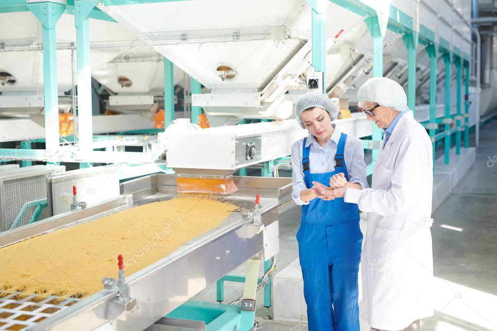 Portrait of two women working at factory  standing by conveyor belt at modern  food production, copy space