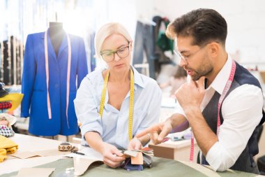Güneş ışığı ile aydınlatılan atölye stüdyosunda çalışırken kumaş ve renk seçen olgun moda tasarımcılarının portresi, kopya alanı