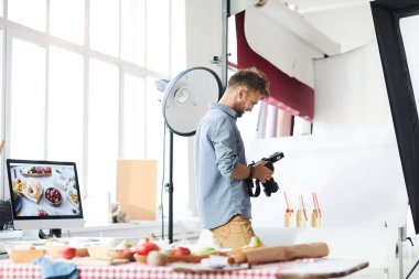 Gıda, kopya alanı çekim fotoğraf stüdyosunda çalıştığınız sırada kamera fotoğraflara bakarken erkek fotoğrafçı gülümseyen portresi