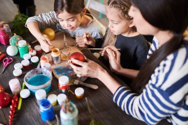 Öğretmen onlara yardım ile işçiliği sınıfında Noel baubles boyama iki küçük kız yüksek açı portre