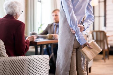 Kafede duran ve müşterilerin siparişini bekleyen garsonun yakın çekimi