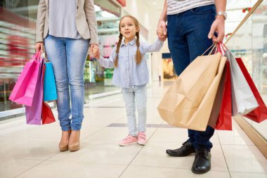 Alışveriş merkezinde mutlu aile alışveriş Portresi, sevimli küçük kız ebeveynleri ile el ele odaklanmak