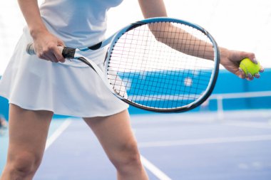 Kapalı kortta tenis oynarken tanınmayan genç kadının orta kesit çekim, kopya alanı