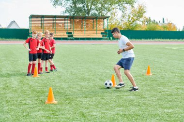 Turuncu koniler, kopya alanı arasında koç lider topu odaklanmak ile Junior futbol takımı eğitim açık havada tam uzunlukta portre