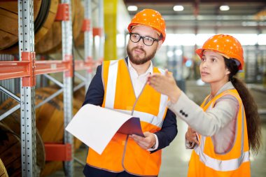 Kadın fabrika işçisinin hardhat giyen sakallı işadamıyla konuştuğu ve işaret ettiği portresi, kopya alanı