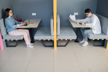Serbest çalışanlar için çalışma alanı: yakışıklı çocuk belgeleri kontrol ederken ve modern ofiste Smartphone kullanarak gözlük dizüstü yazmak ciddi meşgul Bayan