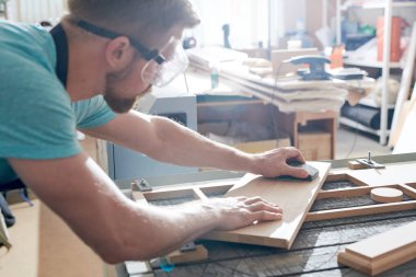 Genç marangoz atölyede zımpara kağıdıyla çalışıyor.