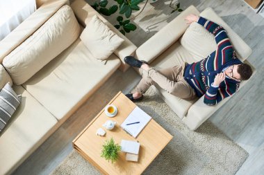 Rahat koltukta oturan rahat giysiler giyen ve rahat ofiste hasta bekleyen gözlük içinde pensive rahat erkek psikiyatrist yüksek açı görünümü