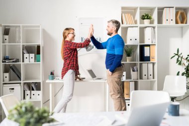 Rahat giyim neşeli iyimser yaratıcı tasarımcılar masada duran ve açık alan ofis başarı kutlarken beş veren