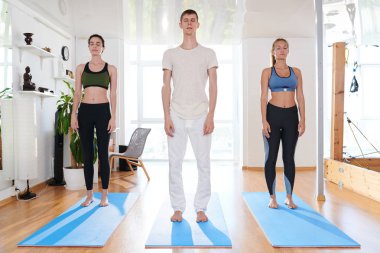 Ciddi sakin yoga öğrencileri ve eğitmen grubu egzersiz paspaslar üzerinde duran ve stüdyoda gözleri kapalı tutmak düşünceleri üzerinde yoğunlaşmıştır