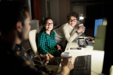 Karanlık ofiste gece çalışırken kahve molası nın tadını çıkaran çok ırklı bir grup insan