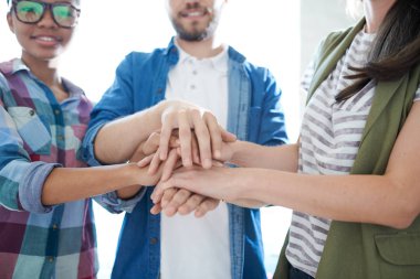 Ofiste takım oluşturma egzersizi sırasında el istifleyen üç gencin orta bölüm portresi, kopya alanı