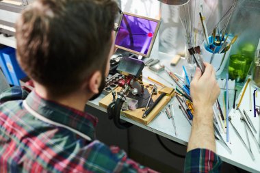 Cam atölyesinde güzel el yapımı takılar için boncuk yaparken gaz meşalesi üzerinde cam şekillendirme adam yüksek açılı portre, kopya alanı