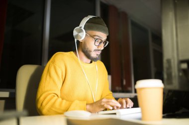Karanlık ofiste bilgisayar kullanarak gece geç saatlerde çalışan çağdaş Orta Doğulu adamın portresi