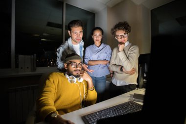 Gece başlangıç projesini bitirirken bilgisayar üzerinde duran yaratıcı insanlardan oluşan ekip