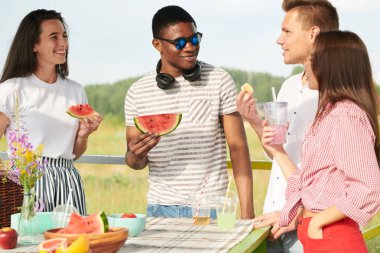 Piknikte karpuz yerken eğlenen bir grup arkadaş