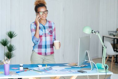 Modern ofiste masa başında duran telefonla konuşan yaratıcı Afrikalı-Amerikalı kadın portresi, kopya alanı