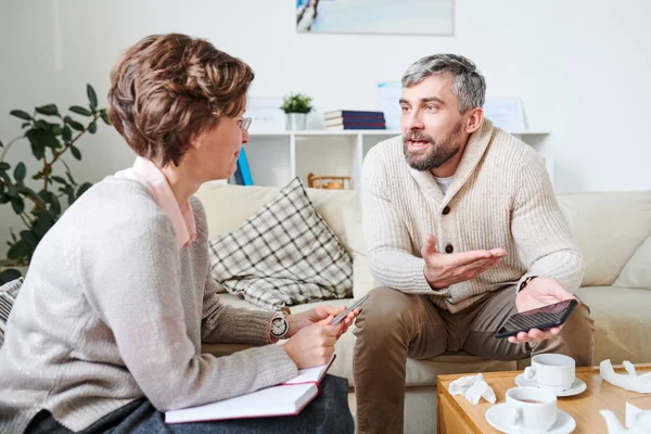 Emotionell Stilig Skäggiga Man Sitter Soffan Och Gest Hand Samtidigt — Stockfoto