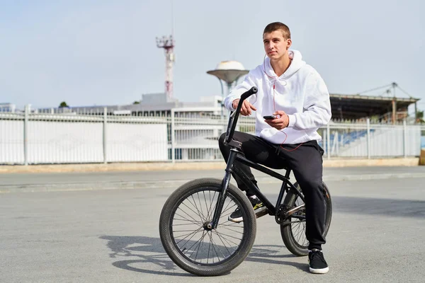 Full length portrait of modern young man riding bmx bike in extreme park, copy space