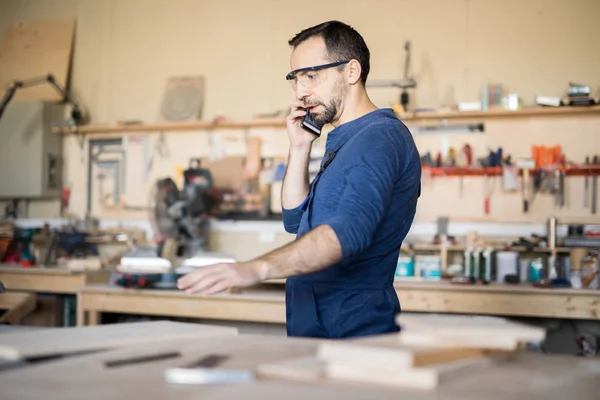 Side View Porträtt Mogna Hantverkare Talar Telefon Medan Arbetar Träbearbetning — Stockfoto