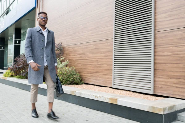 Ciddi yakışıklı moda genç Afrikalı işadamı gri ceket giyen ve mali bölgede güvenle yürürken evrak çantası taşıyan, o ofis bırakarak