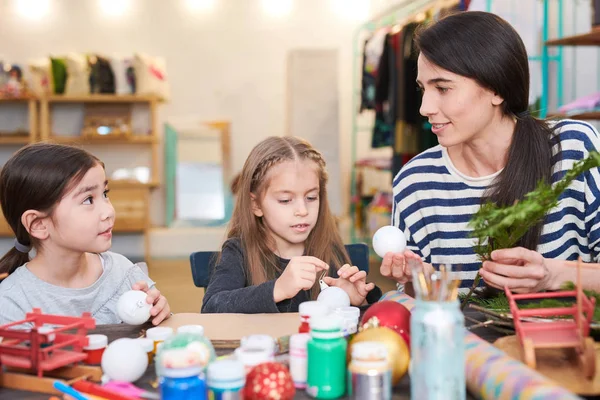 笑顔の女性教師とクラフトクラスでクリスマスの飾りを作る2人の小さな女の子の肖像画 — ストック写真