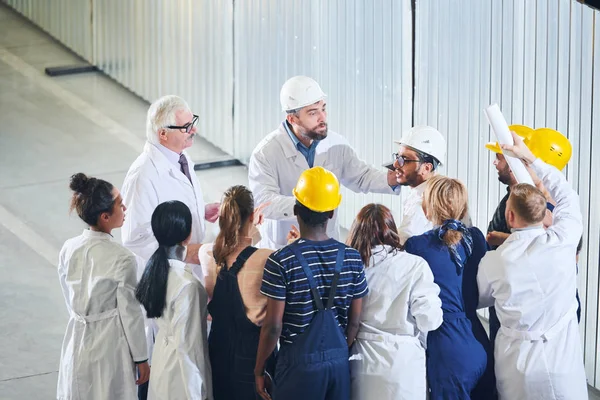 High angle portrait of management meeting with factory workers on strike, copy space