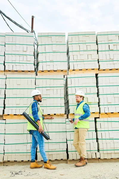 Volledige Lengte Portret Van Twee Bouwarbeiders Bespreken Project Staande Tegen — Stockfoto