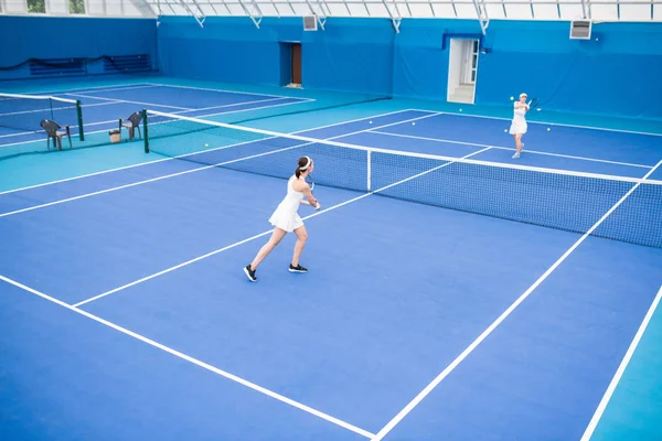 屋内コートでテニスをしている2人の女性の広角ポートレート コピースペース — ストック写真