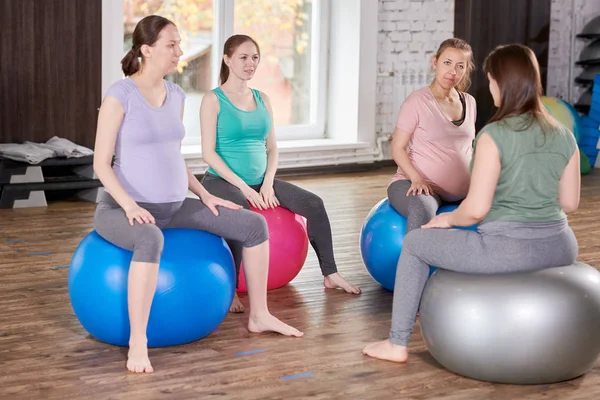 一组孕妇坐在健身球上听产前瑜伽教练的全长肖像 — 图库照片