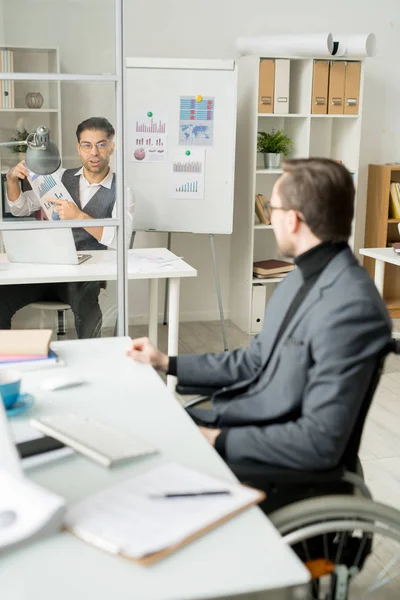 Empresario Sentado Lugar Trabajo Señalando Informe Financiero Discutiéndolo Con Colega —  Fotos de Stock