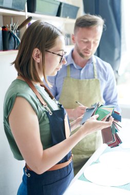 Arka planda meslektaşı ile yeni ürün için kumaş seçimi konsantre kadın terzi yan görünümü