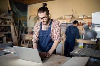 Marangozlar atölyesinde işçilerin Portresi, ön planda dizüstü bilgisayar kullanarak modern adam odaklanmak, kopyalama alanı