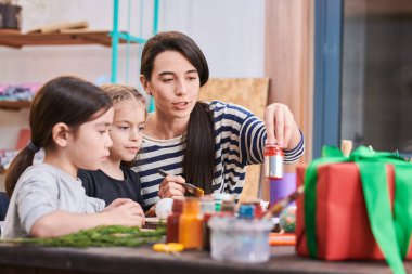 Kadın öğretmen ile işçiliği sınıfında Noel süslemeleri yapan iki küçük kız yan görünüm portresi