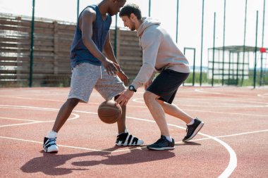 İki genç adamın yan görünüm eylem çekim mahkeme açık havada güneş ışığı ile yaktı basketbol oynarken, kopya alanı