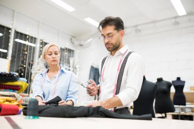 Yakışıklı olgun terzi portresi atölyesinde masada duran giysiler, kopya alanı