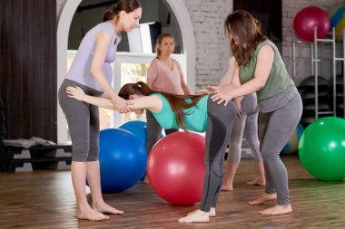 Prenatal yoga sınıfında birlikte egzersiz yapan hamile genç kadınların tam uzunlukta yan görünüm portresi