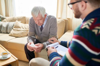 Terapi seansı sırasında psikologla ruhsal sorunları paylaşan dokuları tutan üzgün yaşlı adamın portresi, kopya alanı