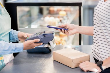 Mağaza veya kafede siparişi için Nfc üzerinden akıllı telefon ile ödeme tanınmayan kadının yan görünümü orta bölümü