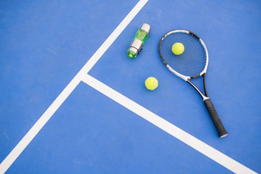 Sarı tenis topu ve raket grafik spor arka plan su şişesi yanında mahkeme mavi katta döşeme, kopya alanı
