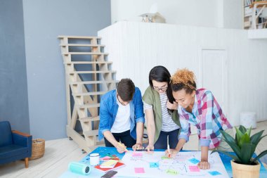 Masa başında duran ve iletişim kuran başlangıç projesini planlarken, çağdaş gençlerin çok ırklı bir grup grafik ve grafik çizmesi, kopyalama alanı