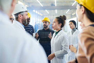 Sanayi atölyesinde grev sırasında üst düzey yönetici bağıran kadın fabrika işçisi yan görünüm portresi, kopya alanı