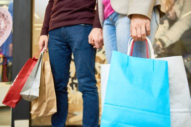 Satış sezonunda alışveriş merkezinde alışveriş çanta tutan tanınmayan çift orta bölüm portre