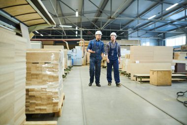 Bitki atölyesi üzerinde yürürken iş hakkında konuşan tulum ve hardhats içerik kendinden emin sanayi işçileri